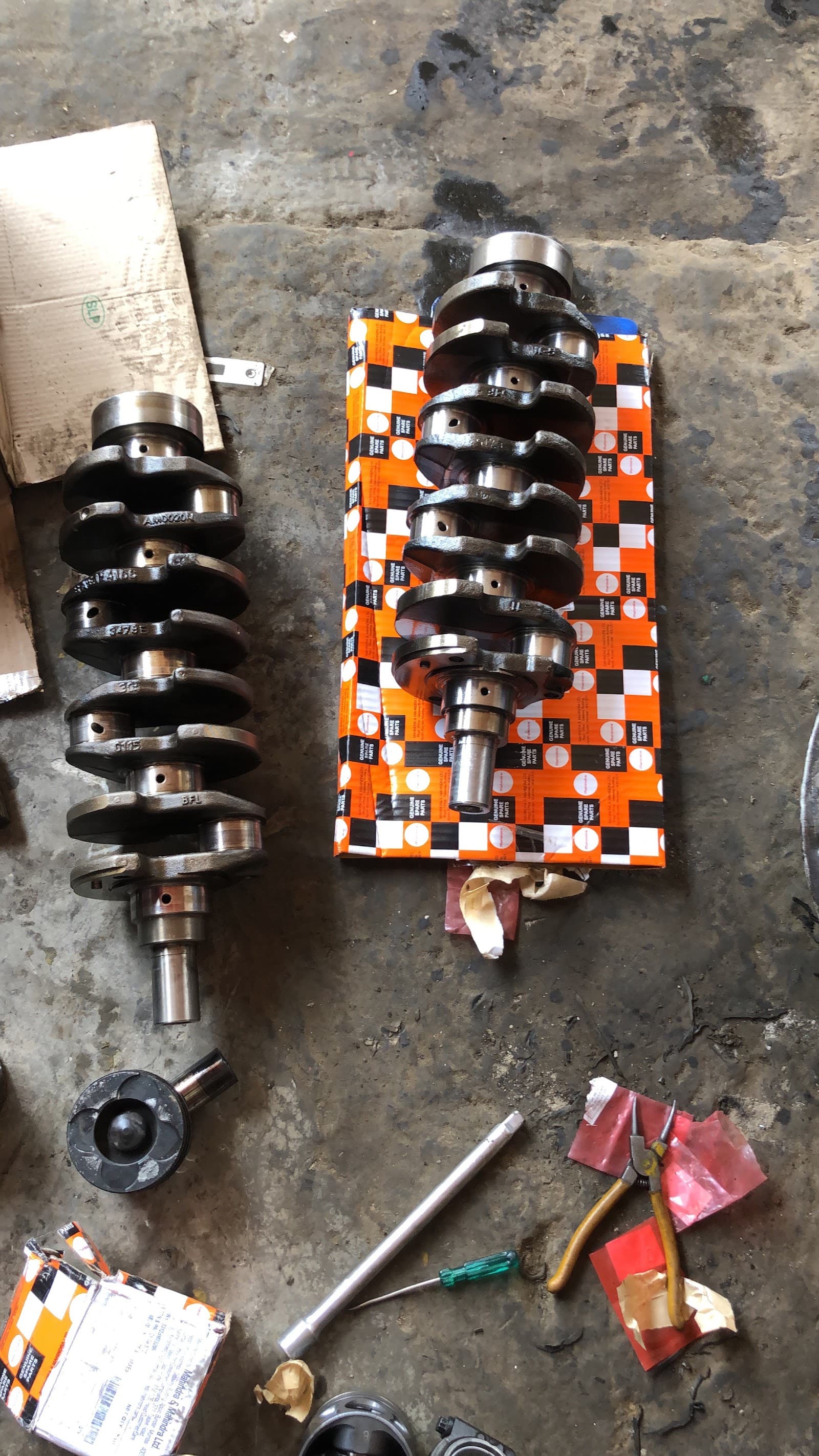 Crankshaft next to new parts in genuine packaging
